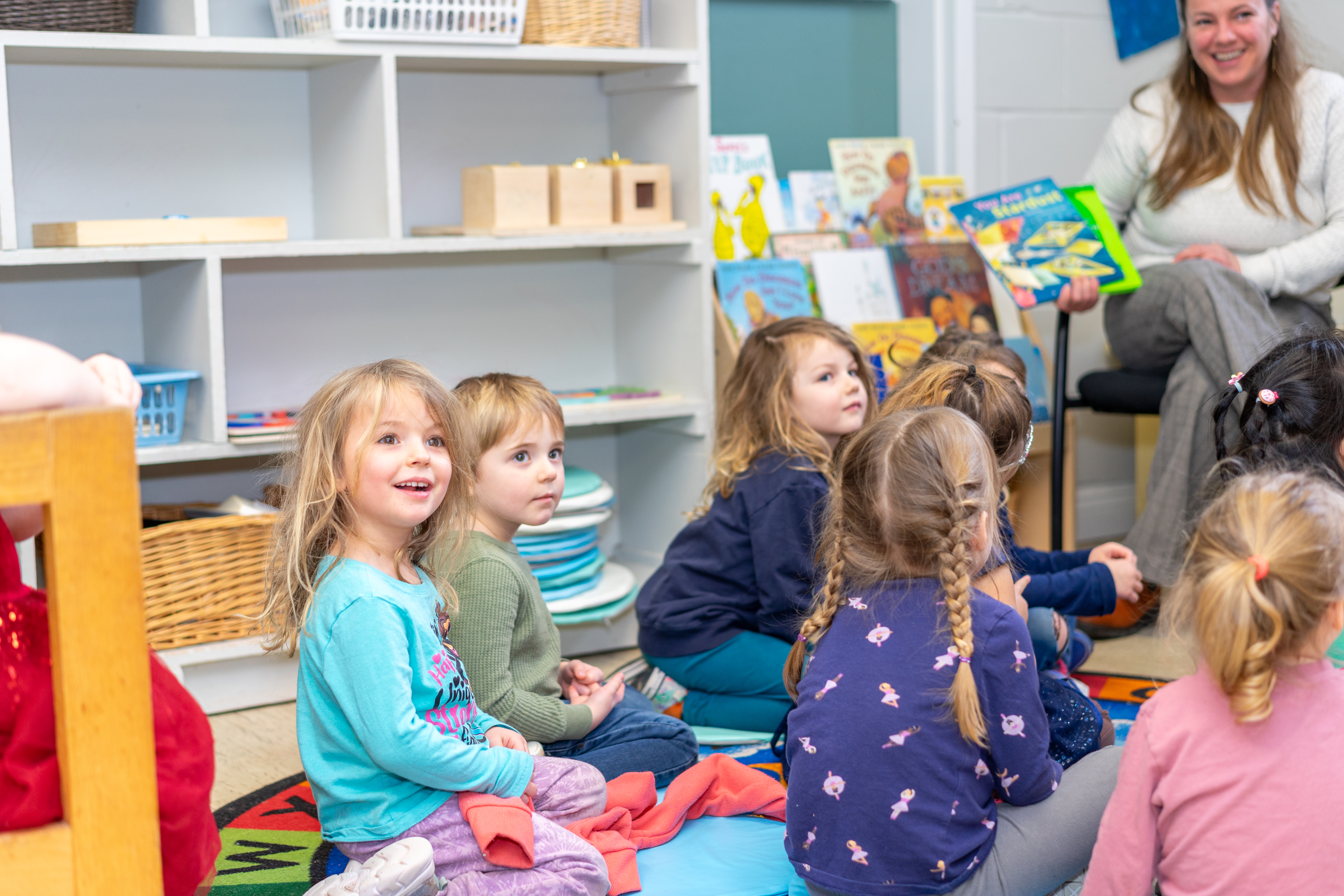 woman reading a book to children sitting on the floor