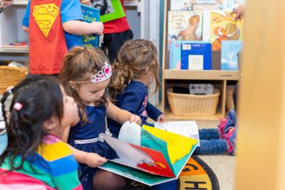 little girl wearing a crown and looking at a book