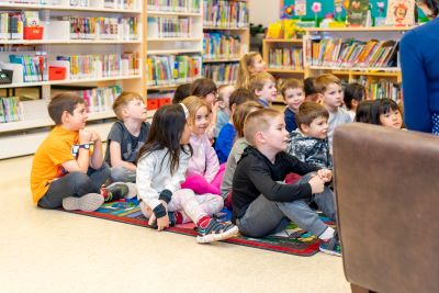 children sitting on the floor listening to someone read them a book