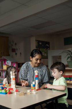 woman playing blocks with two children